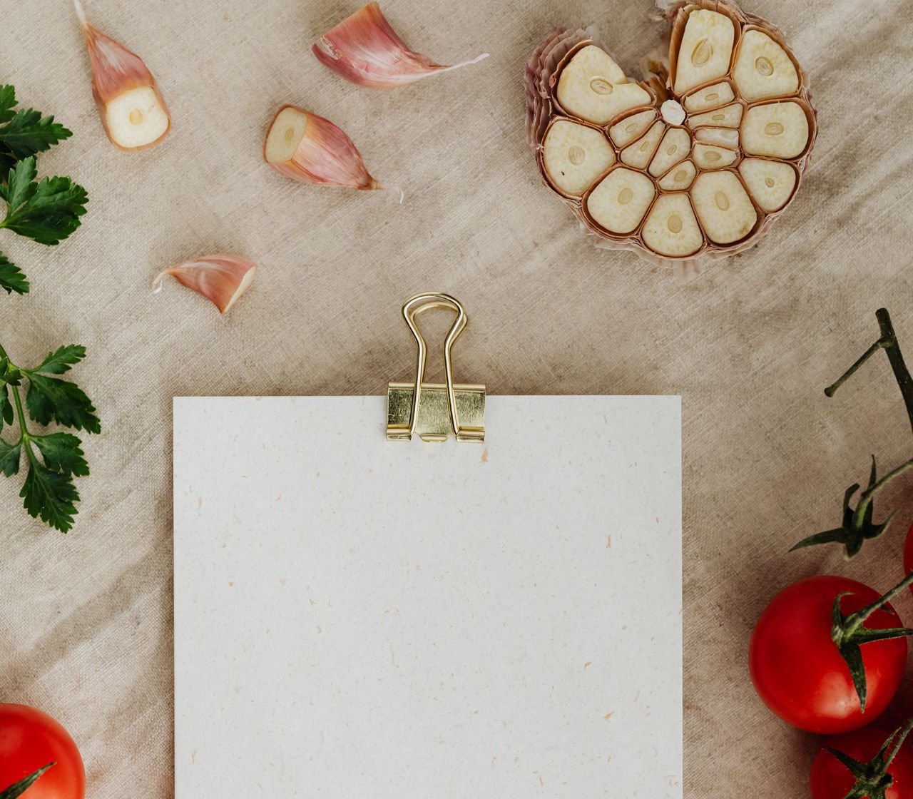 Hoja de menú semanal sobre un mantel de lino con tomates y ajo fresco